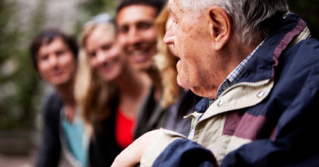 Elderly man telling stories to young people